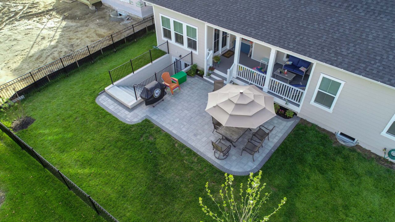 Aerial view of paver patio with open, covered porch