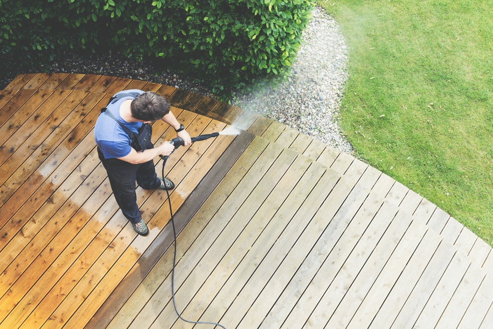 A man showing how to restore faded composite decking.