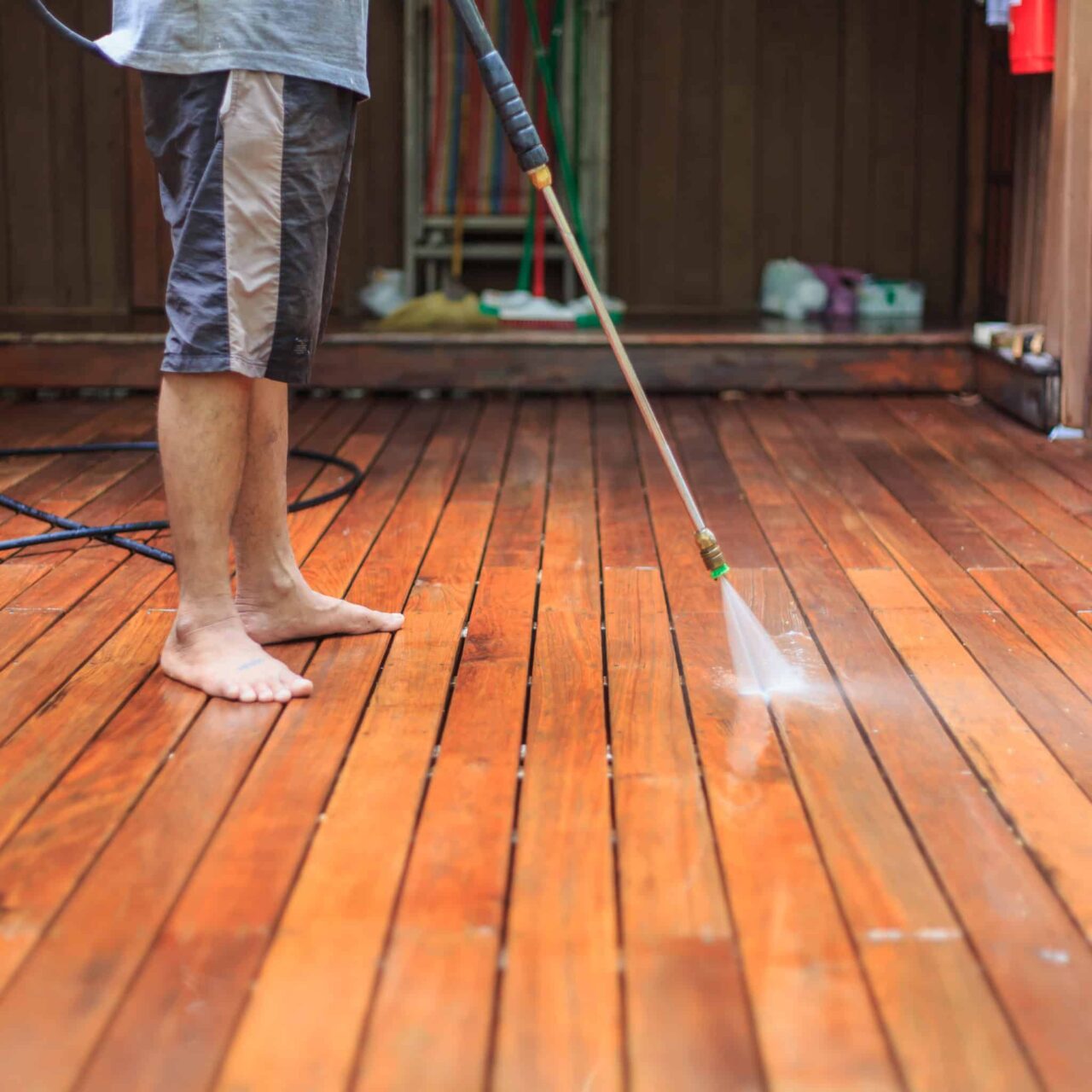 A man pressure washing timber deck