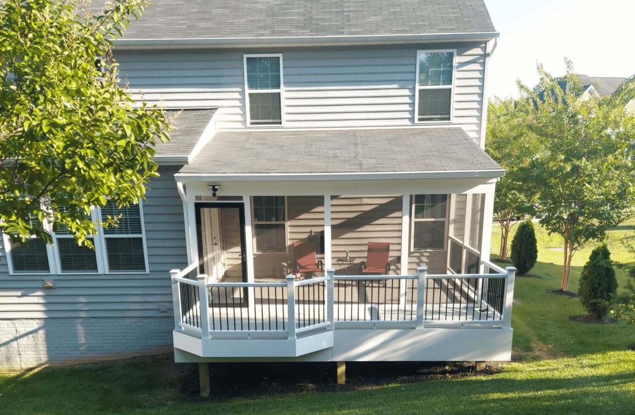 Screened porch with white posts, black railings, and outdoor seating attached to a home by Prince William Home Improvement.