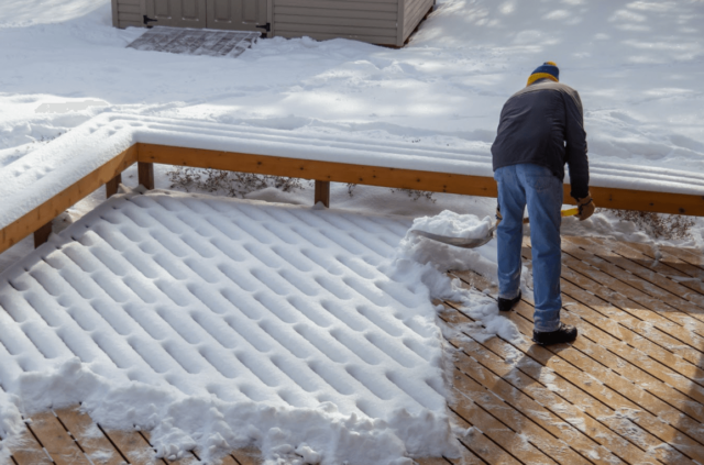 photo of a man shoveling snow on a pressure-treated wood winter-resistant deck