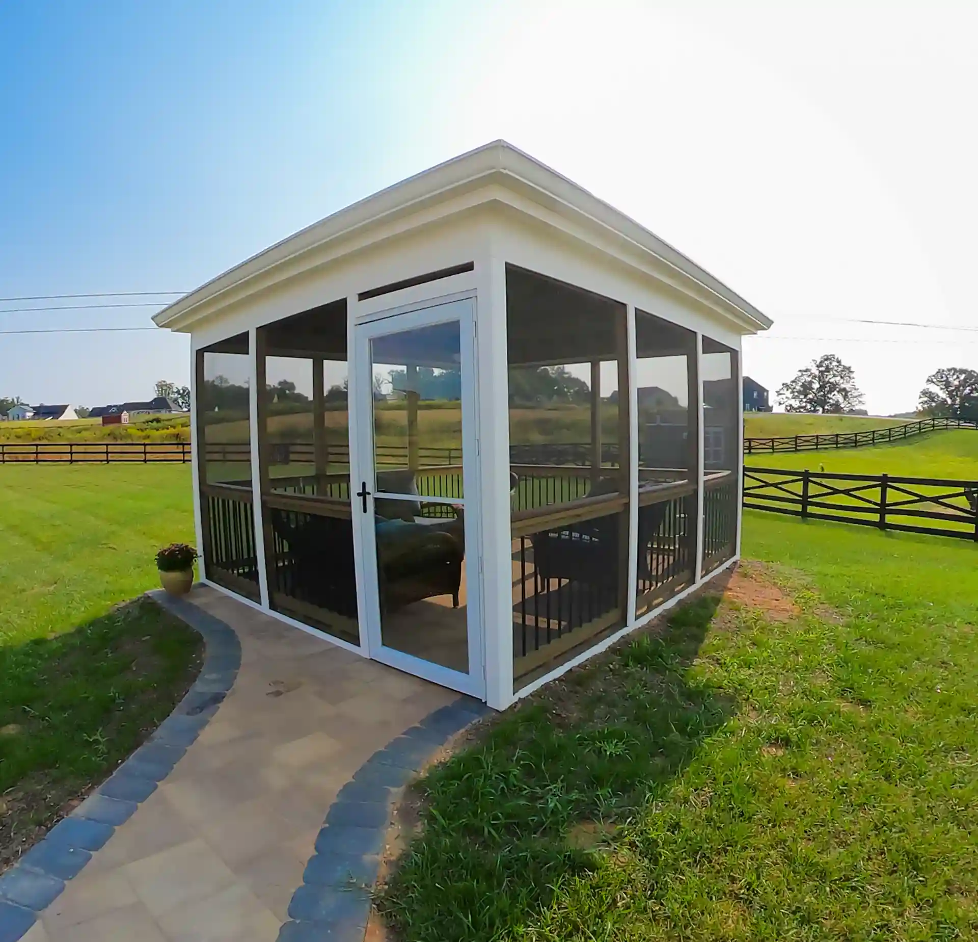 Screened-in outdoor structure with a pathway leading up to it and a view of the surrounding landscape. 