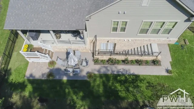 Why Fall is Prime Time for Your Patio Investment Aerial view of a patio with chairs and a table, adjacent to a screened-in porch with stairs leading down to the yard.