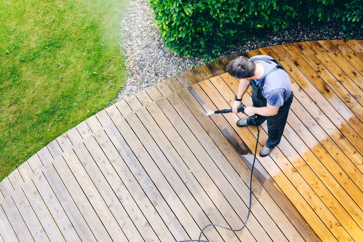 A wood deck being cleaned with a pressure washer