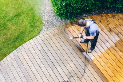 A man cleaning wood deck with a pressure washer