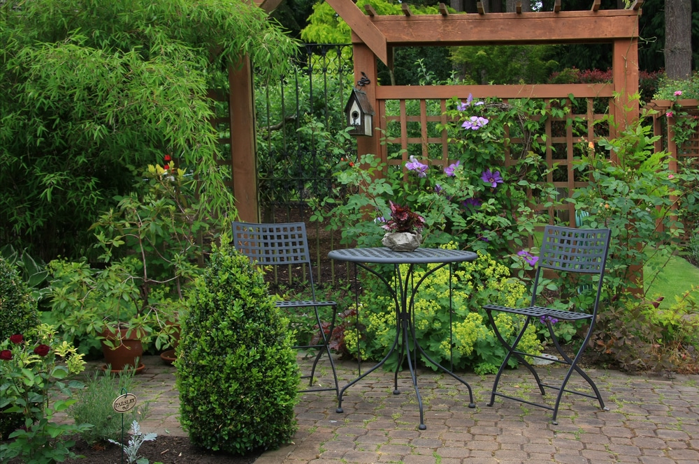 Cozy little back yard patio with table and chairs surrounded by garden