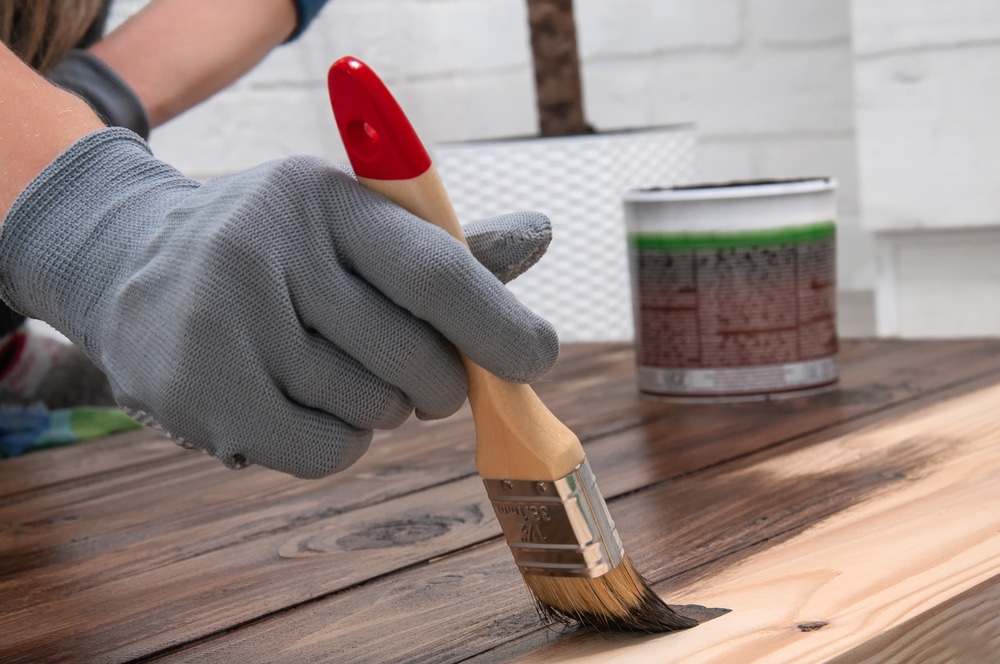 Cropped image of hand with a brush shows on how to treat timber decking.